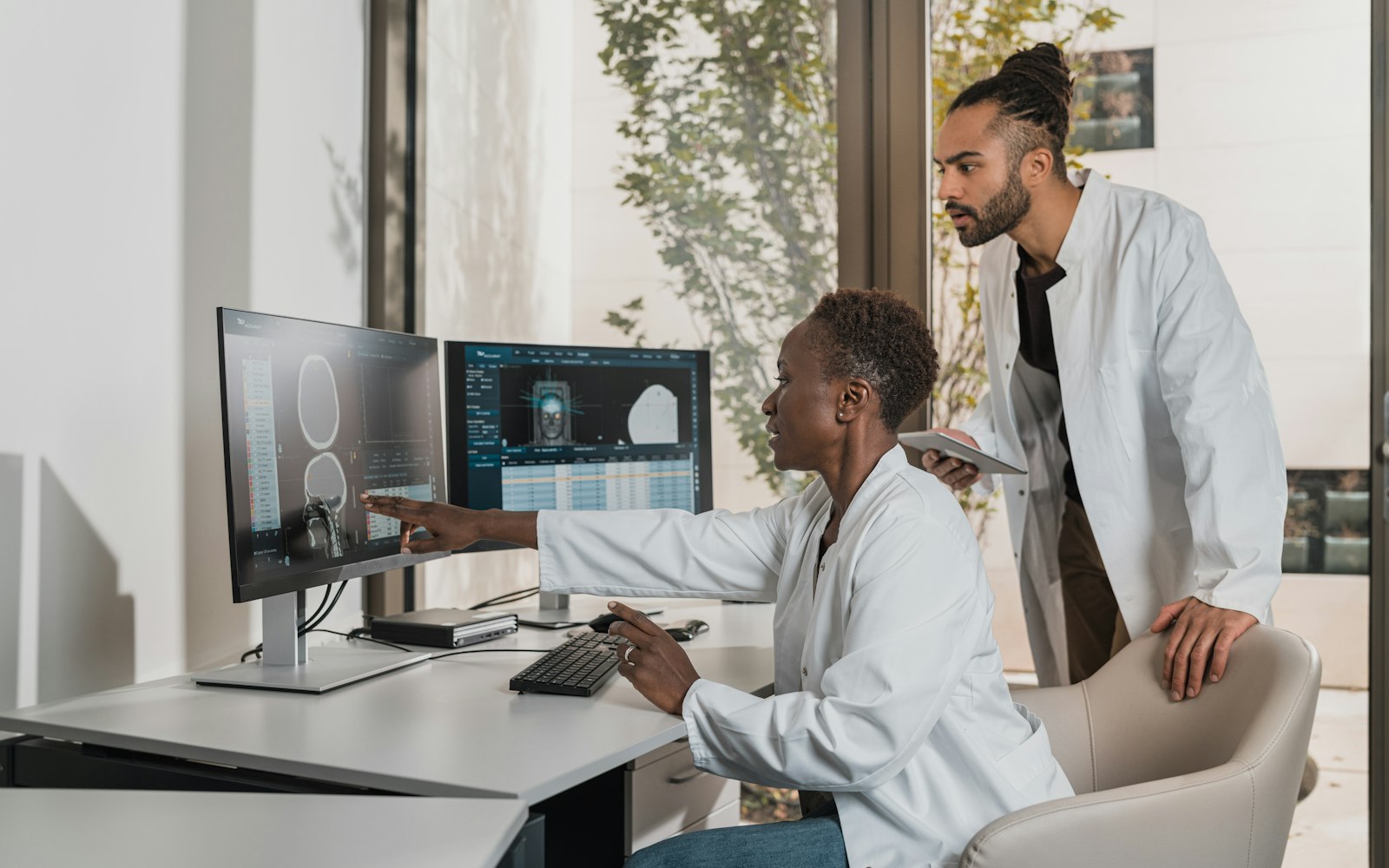 Clinicians reviewing patient data on dual screens — FHIR vs HL7v2 interoperability